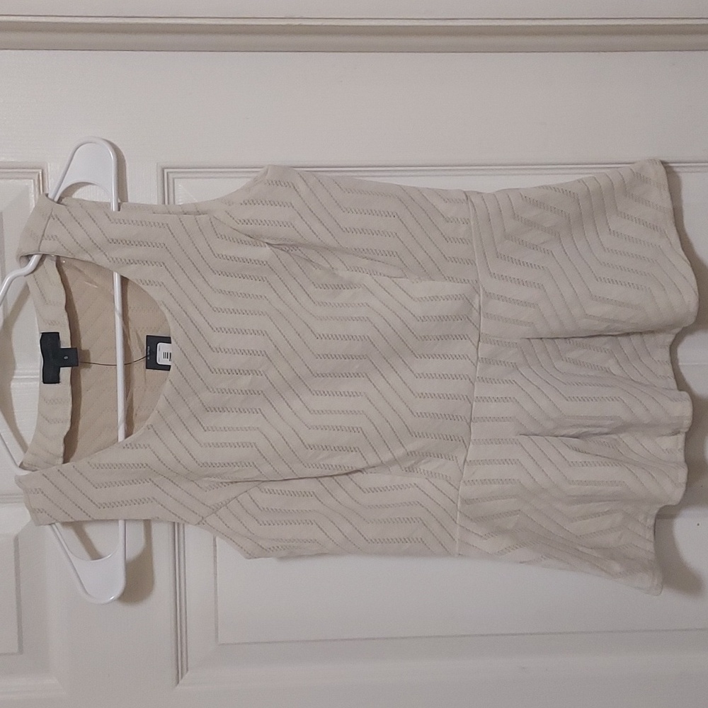 Short sleeved cream colored peplum top with woven detail